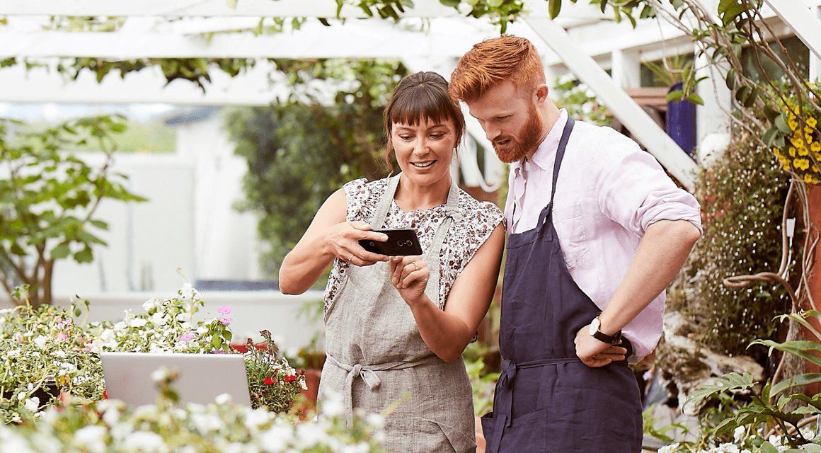 Two people looking at a mobile phone in a garden