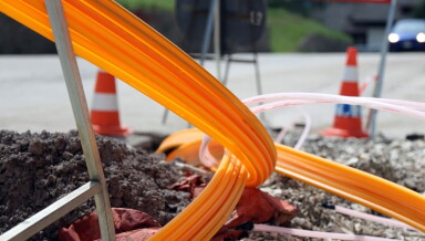 Long optic fibre cables being put underground by a roadside.
