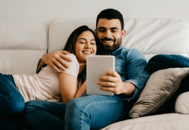 Couple on couch looking at a tablet.