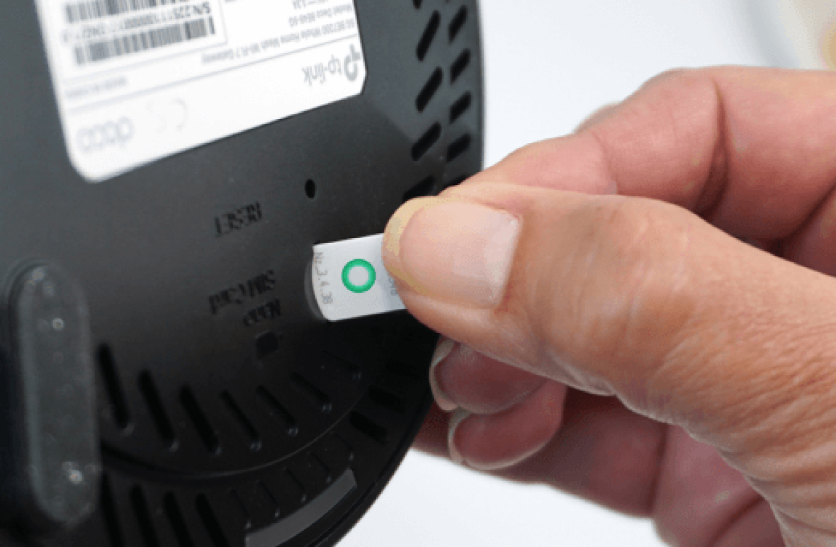 Hand inserting a SIM card into the back of a modem.