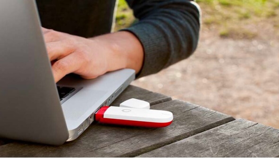 Guy using a laptop which has a Vodem stick connected.