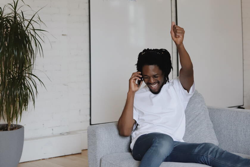 A man raising his arm in celebration while on a phone call