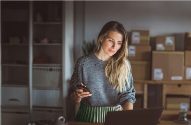 A woman in her small shop, quietly checking inventory on her laptop.