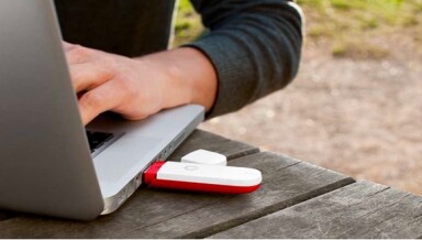 Guy using a laptop which has a Vodem stick connected.