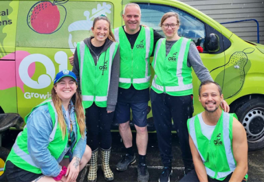 Five Oke volunteers pose in front of a colourful branded van.