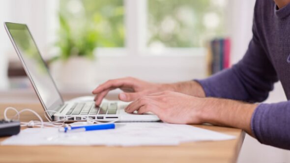 Man typing on a laptop at a desk.