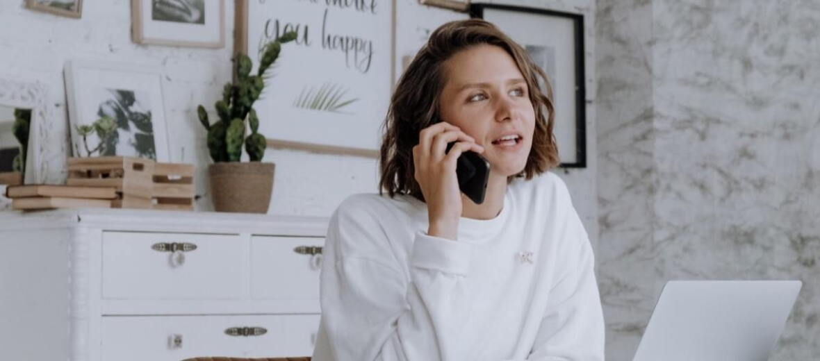 woman sitting in front of laptop while on the phone