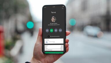 Hand holding a phone to top up their plan
