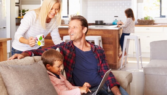 A small family, with parents helping two kids with online homework.
