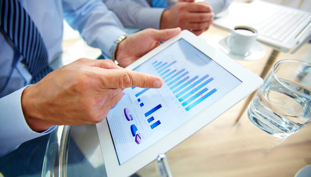 Man pointing to graph on a tablet screen.