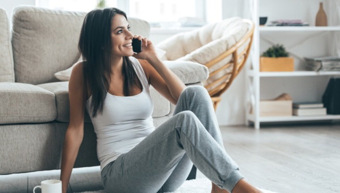 A woman relaxing and talking on her home phone.