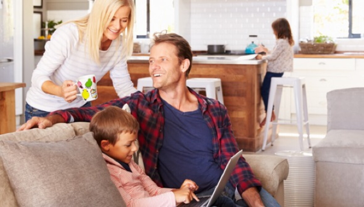 A small family, with parents helping two kids with online homework.