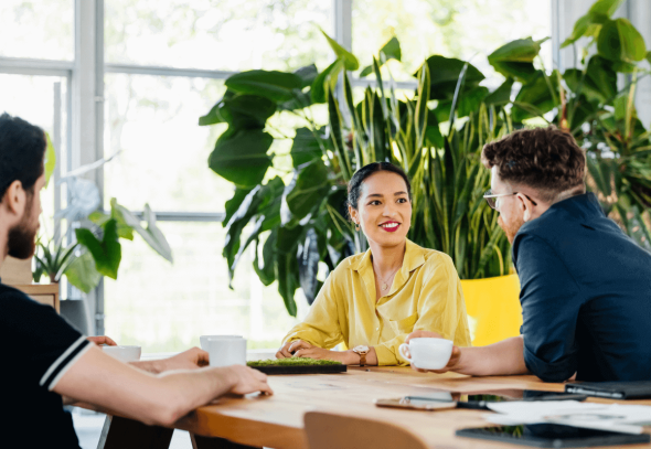 A group of three people sitting at a table and having discussions.