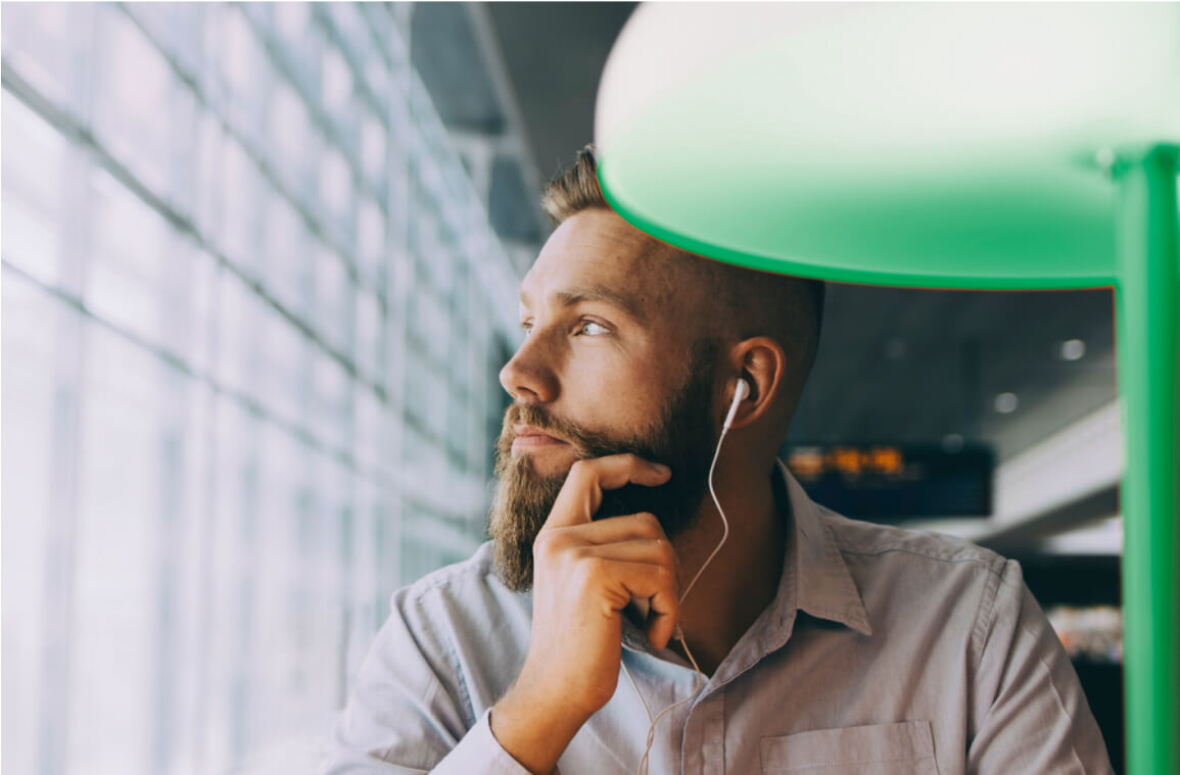 A pensive bearded man listening to a Teams meeting at his desk.