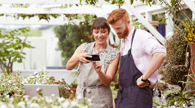Two people looking at a mobile phone in a garden