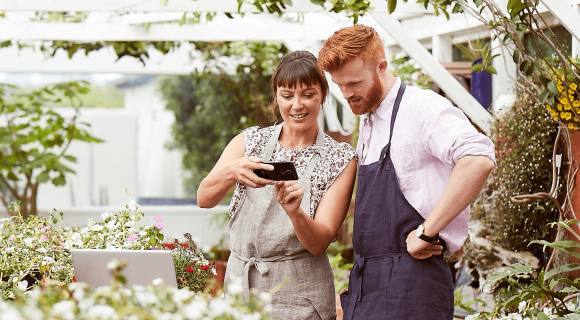Two people looking at a mobile phone in a garden
