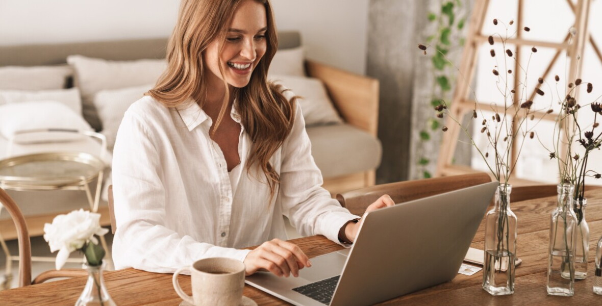woman sitting at desk and smiling at laptop