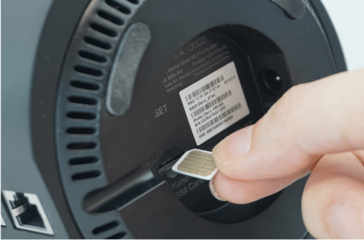 Person inserting SIM card at the bottom of Deco X80-5G modem