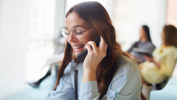 A smiling woman answering the phone in an office