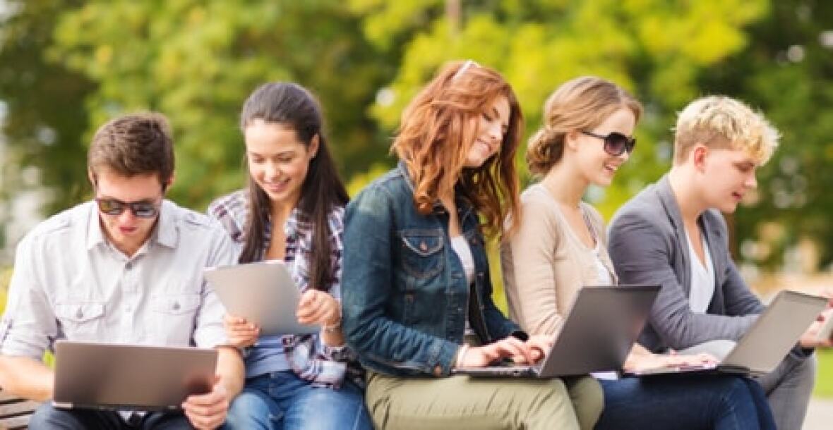 A group of students sitting at a park using their laptop.