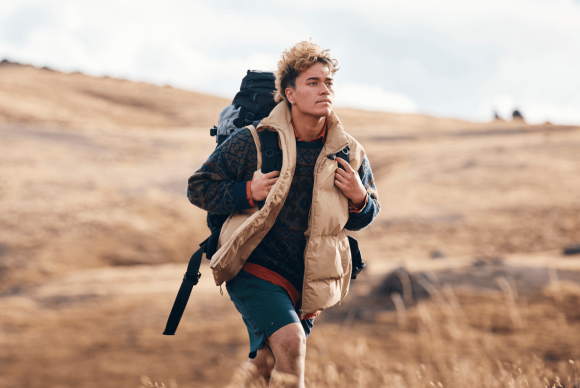 Jade walking down a grassy hill with a backpack