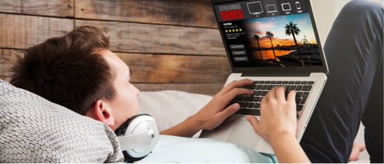 A man lying back on a couch while using his laptop with Fibre Max.