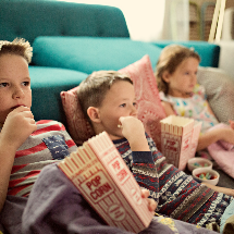 kids eating popcorn on floor watching a movie