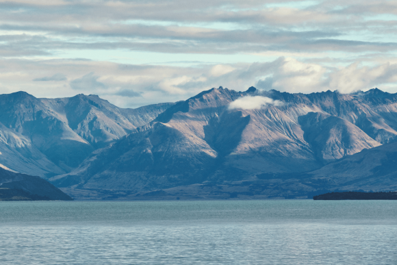 Scenic mountain range and lake under a cloudy sky with dramatic natural landscape views.