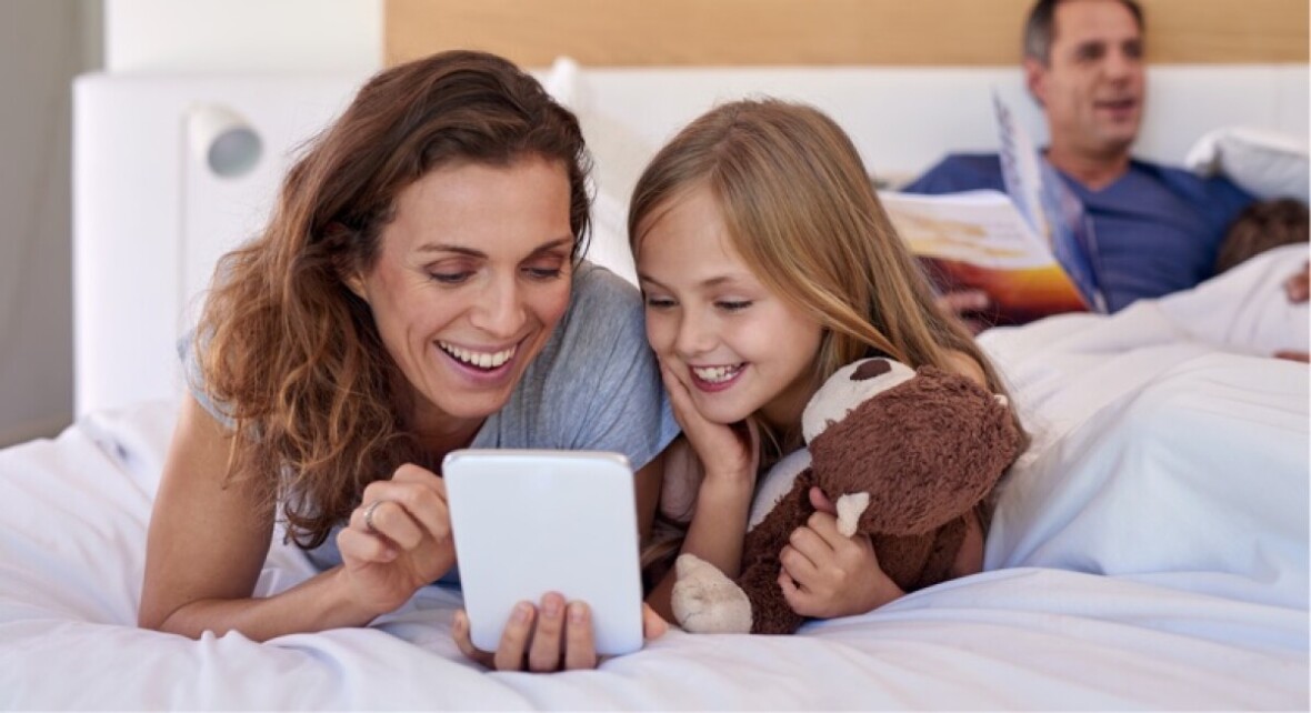Woman and her daughter looking at a digital tablet and smiling.