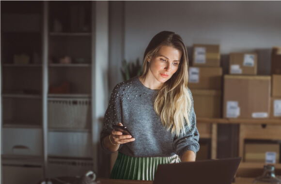 A woman in her small shop, quietly checking inventory on her laptop.