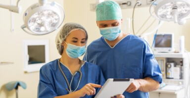 Two doctors looking at a report on a digital tablet.