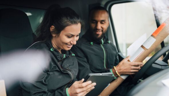 Two delivery drivers checking the delivery address from inside their van.